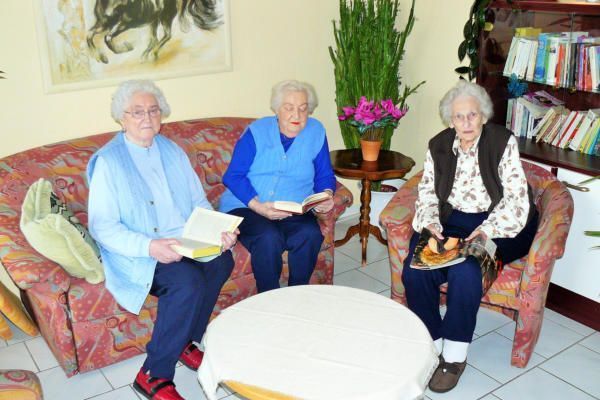 Drei ältere Frauen sitzen auf einer Couch und lesen Bücher