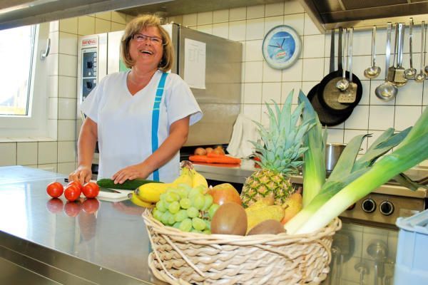 Eine Frau in einer Küche mit einem Korb voller Obst und Gemüse