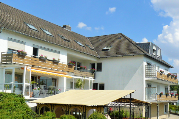 Ein großes weißes Gebäude mit einem braunen Dach und Balkonen