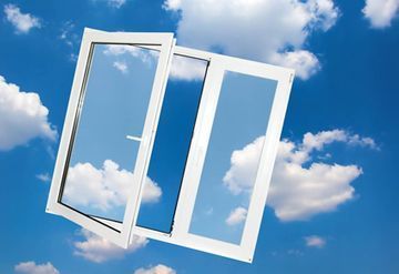 Dos ventanas blancas están abiertas a un cielo azul con nubes.