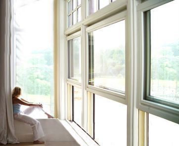 Una mujer está sentada en una cama mirando por una ventana.