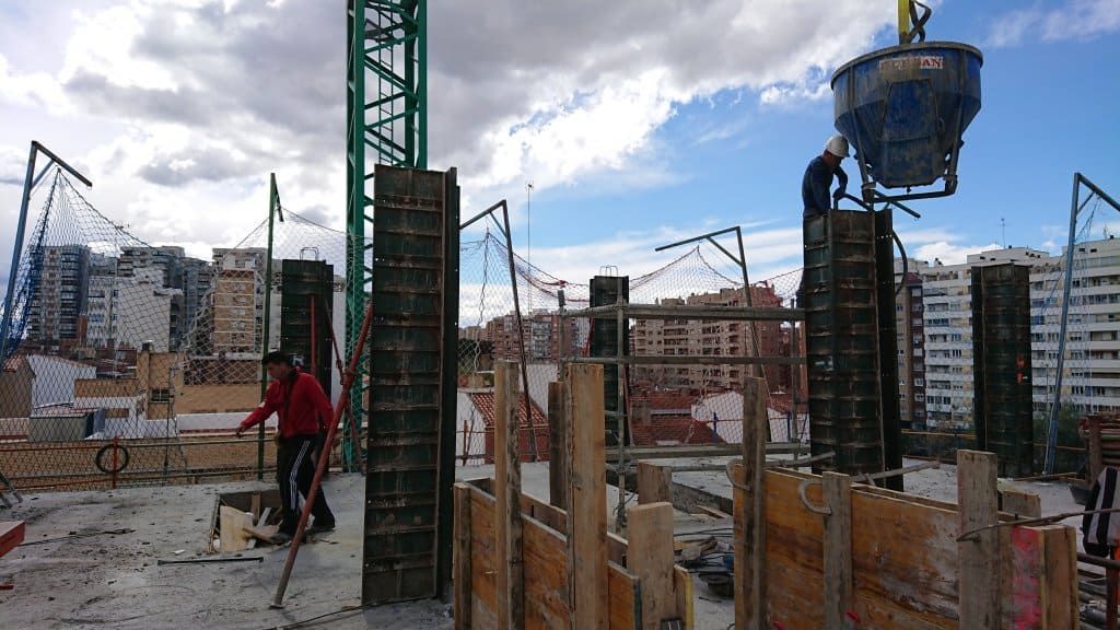 Una obra en construcción con una grúa verde al fondo