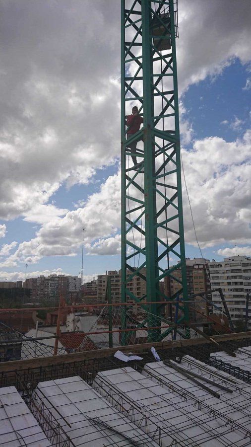Un hombre está parado encima de una grúa verde.