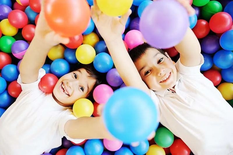 Un niño y una niña están jugando en una piscina de pelotas.