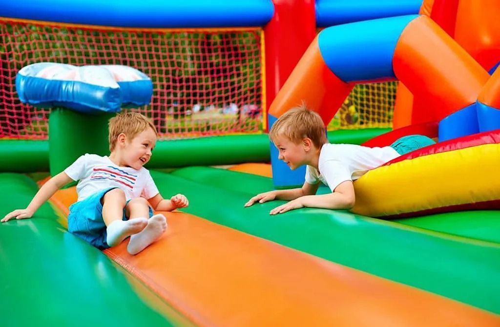 Dos niños pequeños están jugando en un parque inflable.