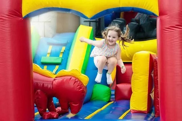 Una niña está saltando en una casa inflable.