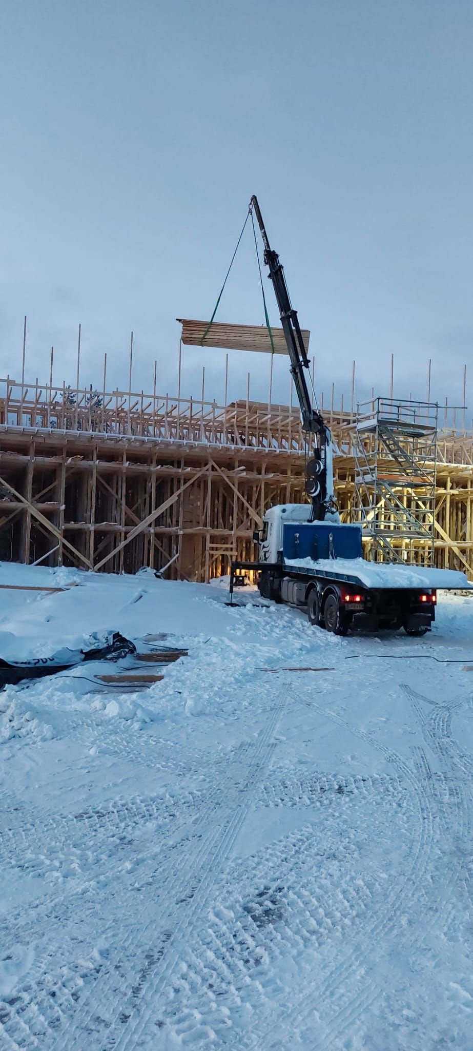 Rakennusmateriaalien nosto Hiab-nosturilla talvella. Tehokasta logistiikkaa ja rakentamista Lapin olosuhteissa.