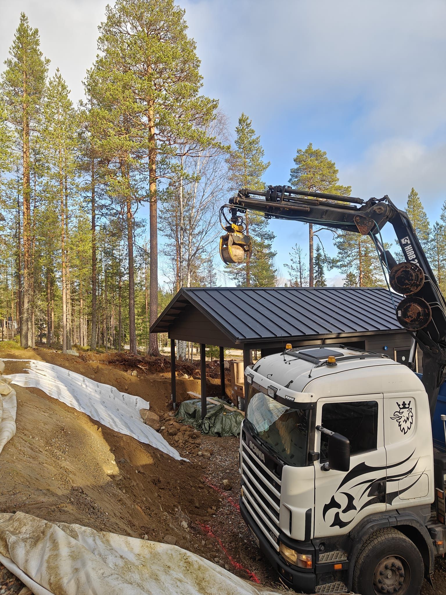 Piharakentaminen ja maisemointi Hiab-nosturilla. Lapin Rakennustyö Oy toteuttaa vaativat huvilaprojektit ja nostotyöt.