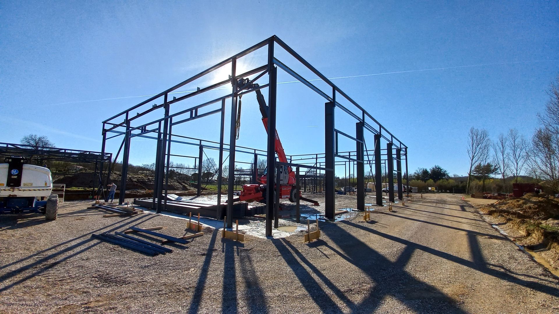 Structure en acier d'un bâtiment en construction à l'extérieur, avec un ciel bleu clair.
