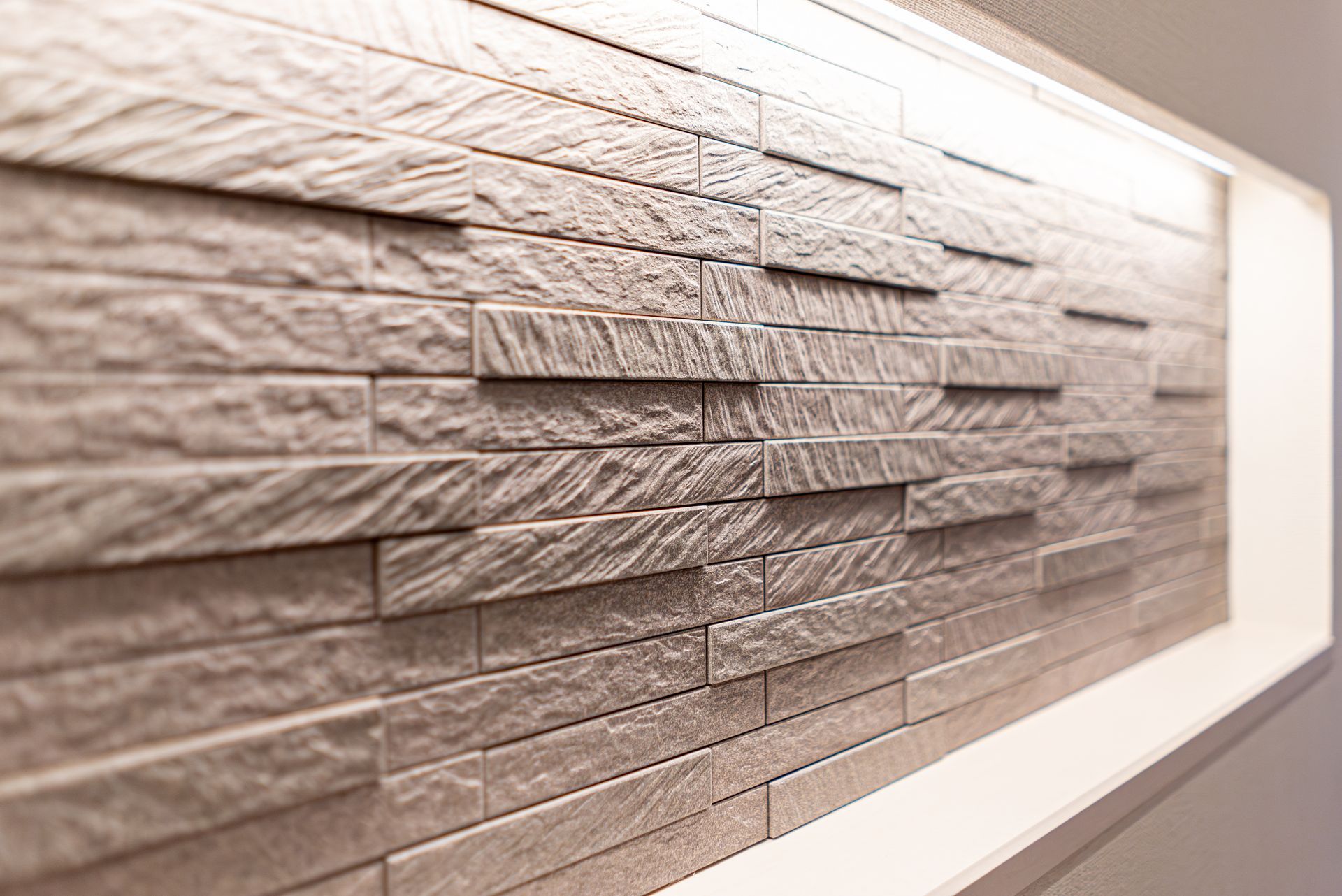 Mur de briques grises texturées avec un luminaire encastré.