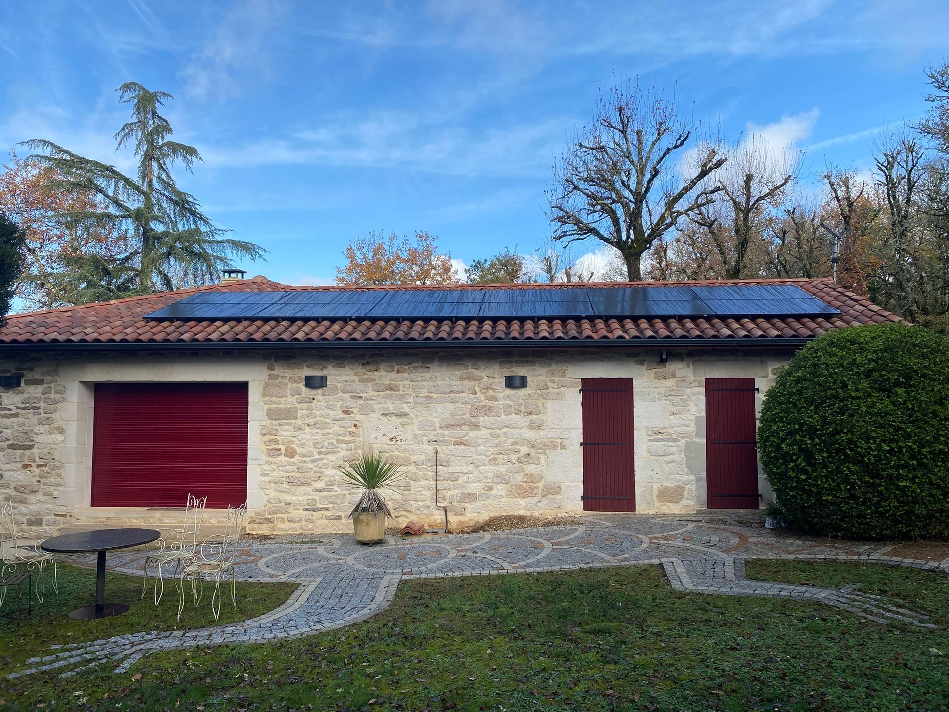 Panneaux solaires sur le toit d'une maison, antenne parabolique, ciel bleu et arbre vert.