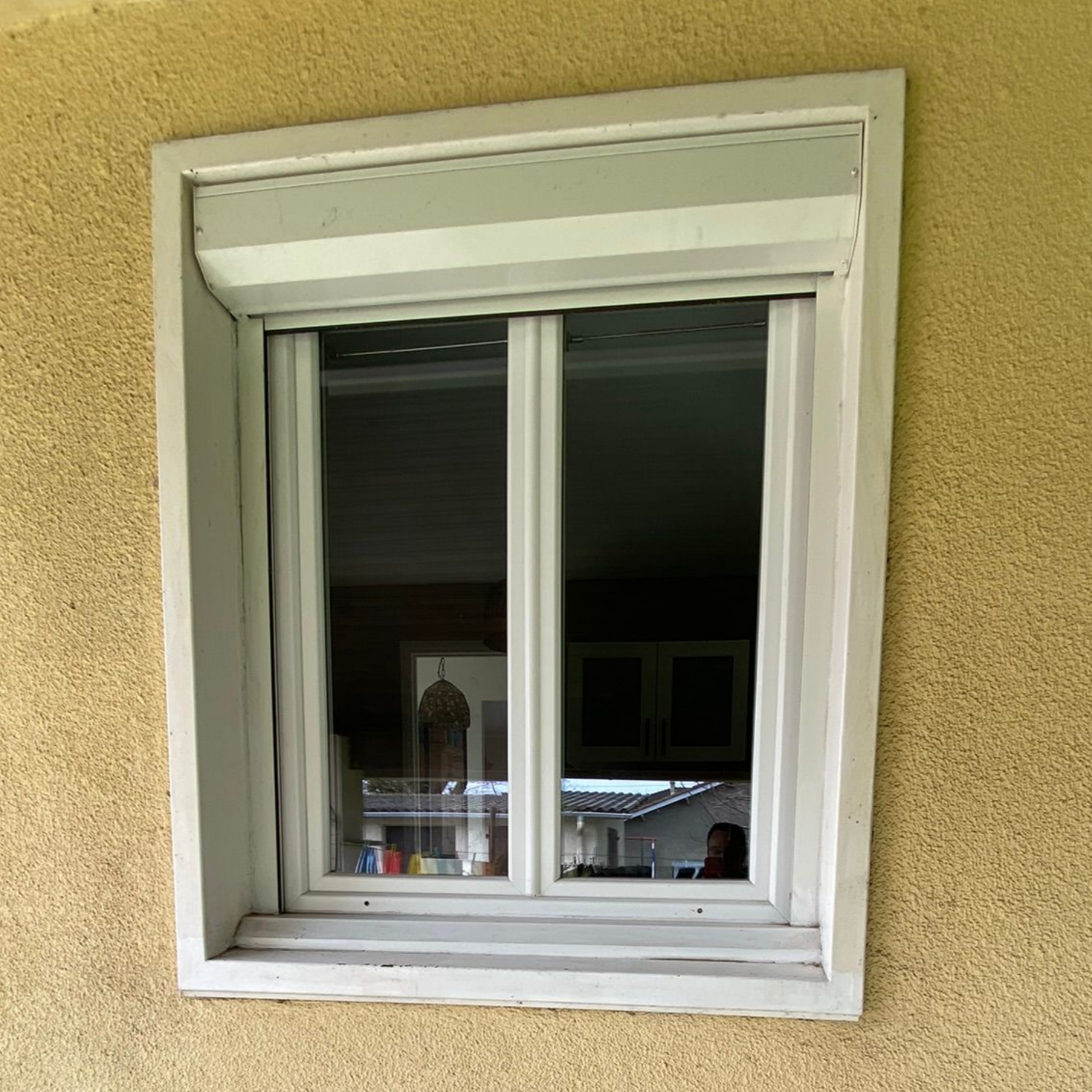 Fenêtre à cadre blanc à trois carreaux ; lumière du soleil, rebord de fenêtre intérieur, arbres verts visibles à l'extérieur.