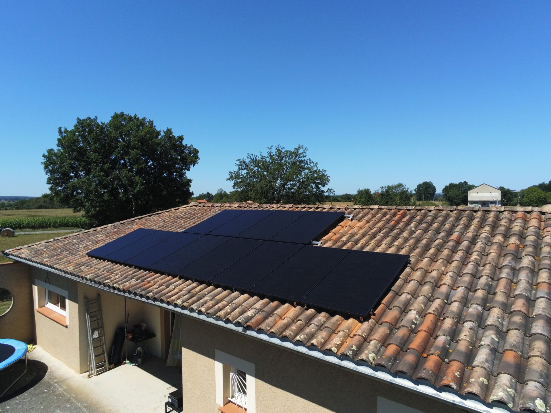 Panneaux solaires installés sur le toit en tuiles de terre cuite d'une maison par une journée ensoleillée.