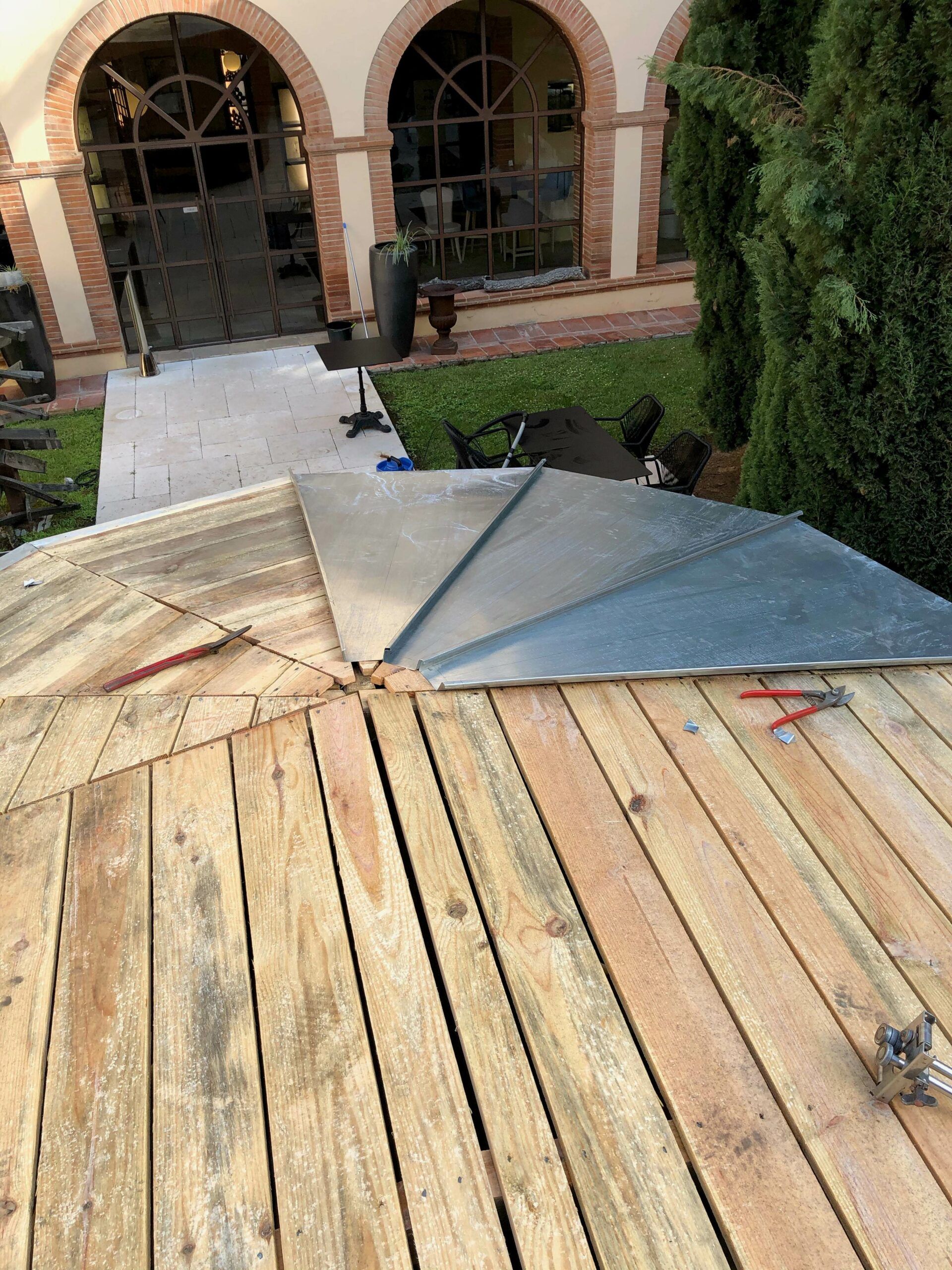 Toiture de gazébo en bois en construction avec tôle partiellement installée.