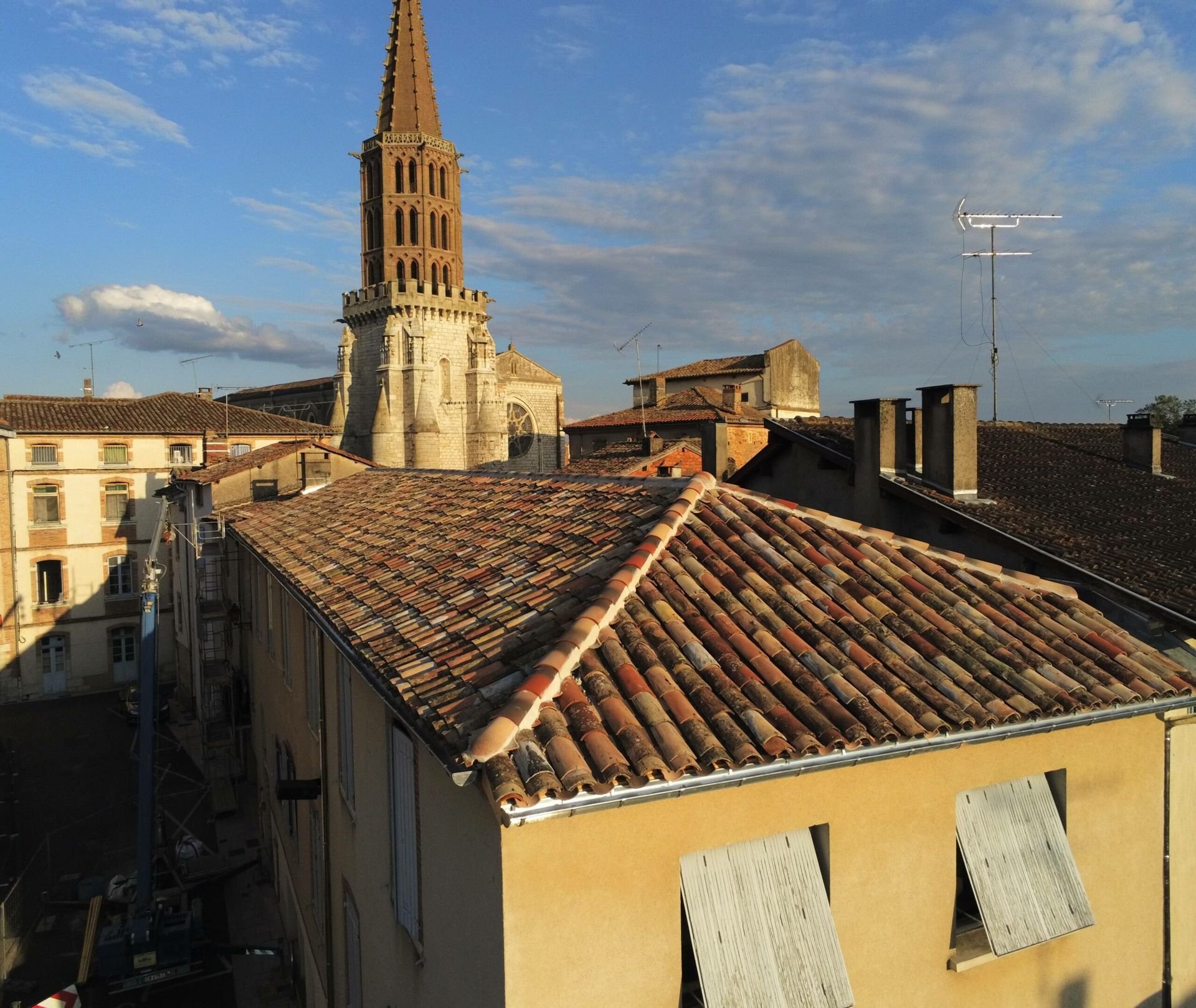 Toits de vieux bâtiments d'une ville européenne, avec un clocher. Journée ensoleillée, ciel bleu.