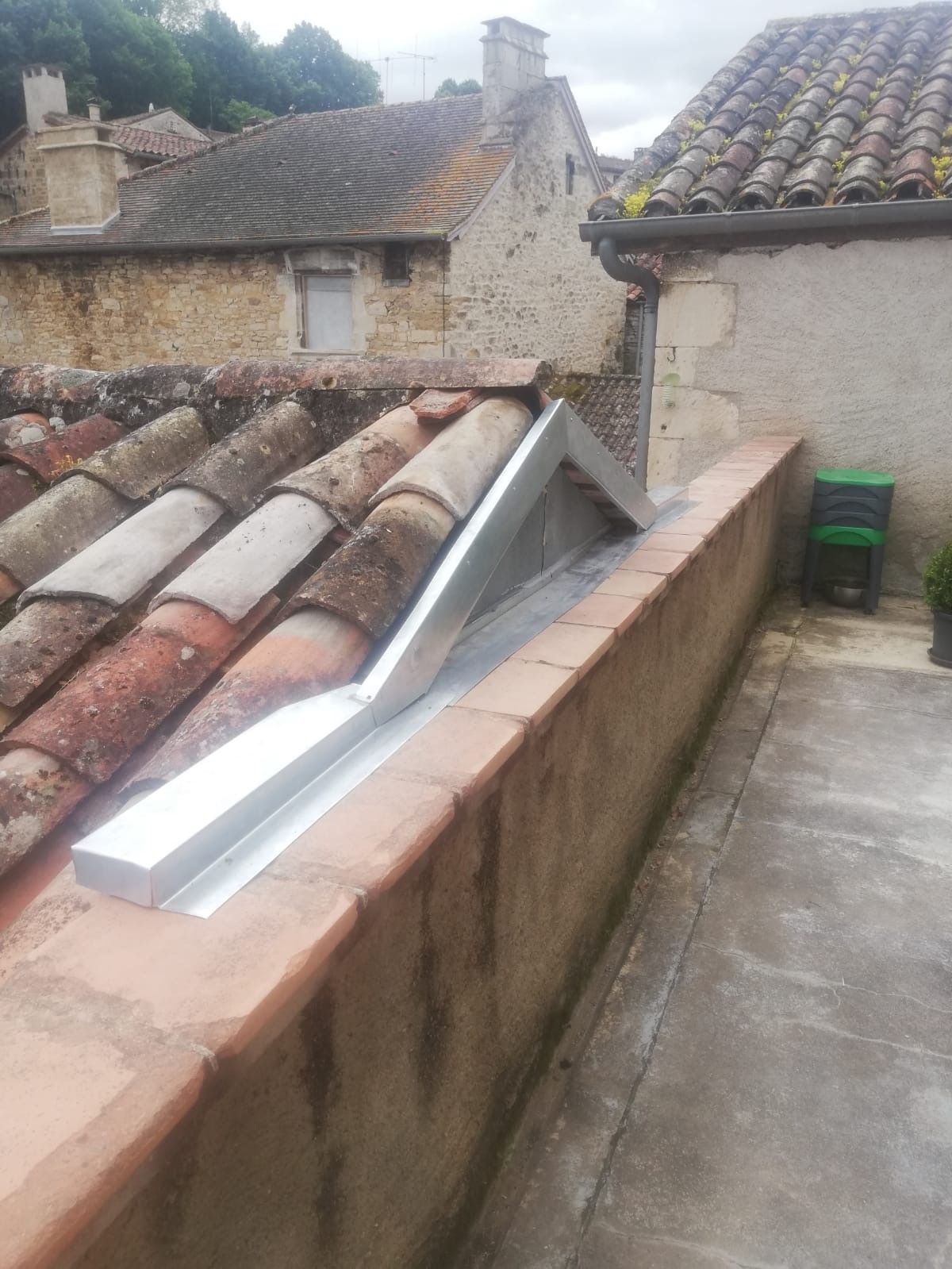 Vue du toit avec solin métallique incliné le long d'une corniche en terre cuite. Bâtiments et toits de tuiles en arrière-plan.