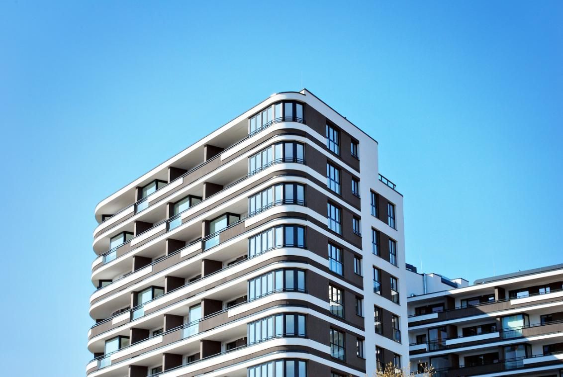 Un moderno edificio de apartamentos de varias plantas con balcones curvos y paneles de fachada oscuros