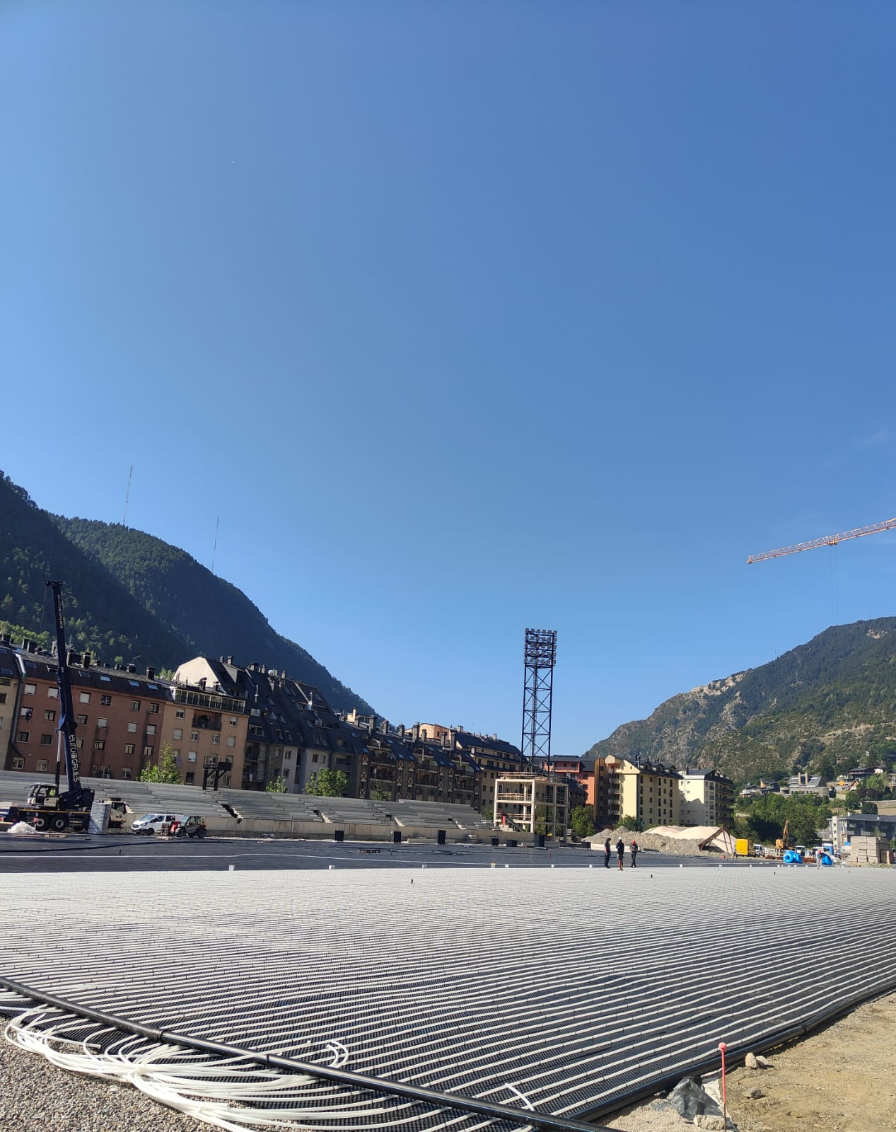 Un sitio de construcción con un cielo azul y montañas al fondo.