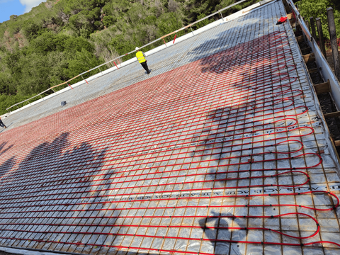 Un hombre está parado sobre un piso de concreto con una rejilla de cables.