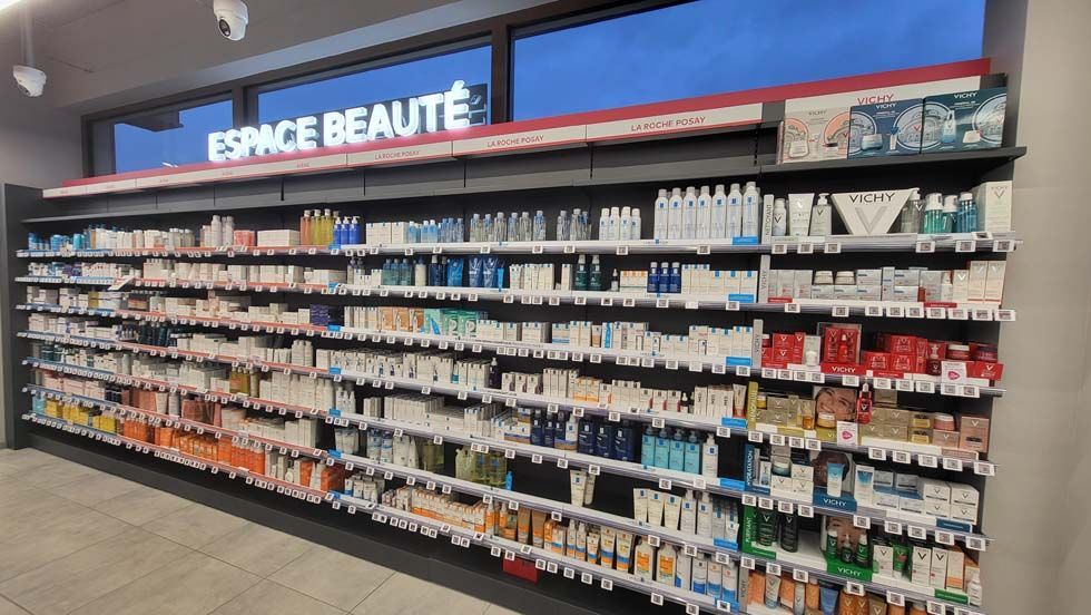 Présentoir en rayon dans un magasin, portant l'étiquette « Espace Beauté », rempli de produits de beauté.