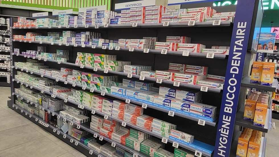 Rayons de produits d'hygiène bucco-dentaire dans un magasin ; on y voit différentes marques et emballages.