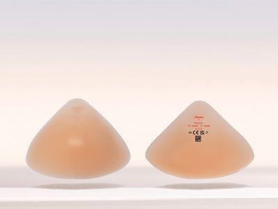 Deux prothèses mammaires compensation totale couleur chair en forme de larme, dont l'une porte l'étiquette du produit.