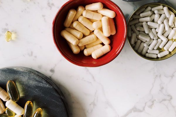 Des bols de pilules de couleurs variées disposés sur une surface en marbre.