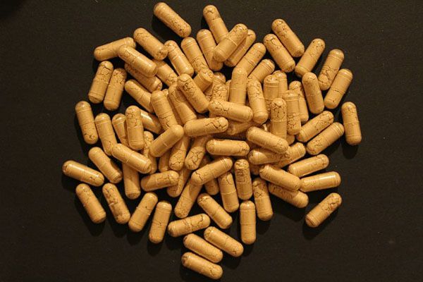 Un amas de capsules brun clair sur une surface sombre.