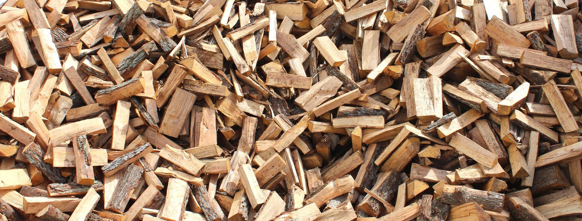 Tas de bûches et de copeaux de bois dans les tons bruns et beiges.