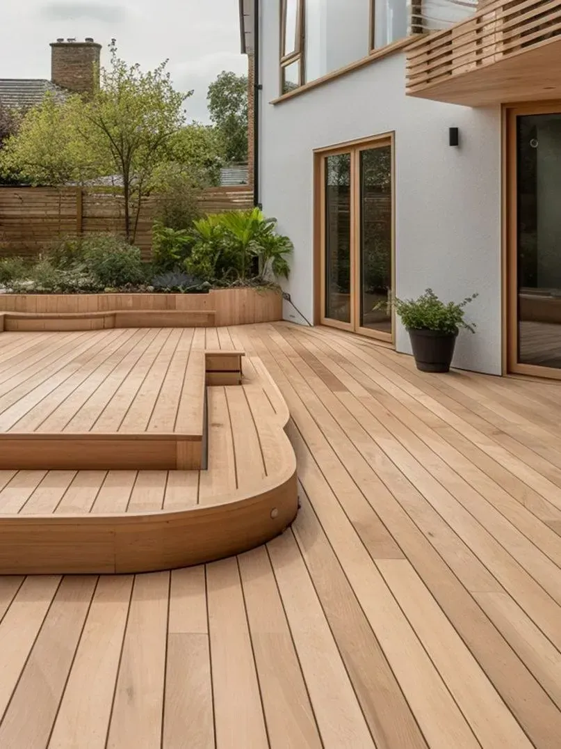 Terrasse moderne en bois avec banquette incurvée, jardinières et portes coulissantes en verre jouxtant une maison.