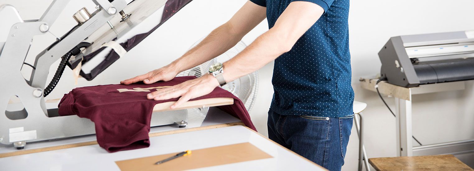 Homme qui utilise une presse pour floquer un T-shirt rouge