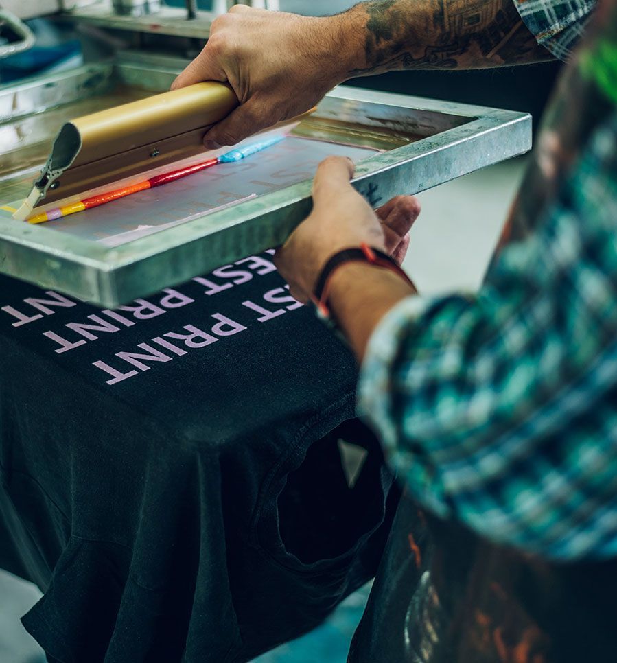 Homme qui imprime un t-shirt en sérigraphie