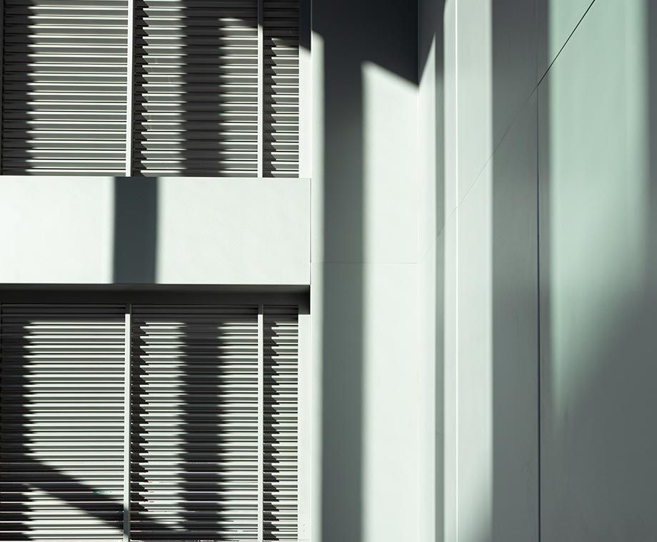 Détail architectural extérieur avec stores et ombres marquées.