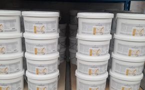 Auf einem Ladenregal standen Stapel weißer Plastikbehälter mit Etiketten, vermutlich Behälter mit Farbe oder Dichtmasse.