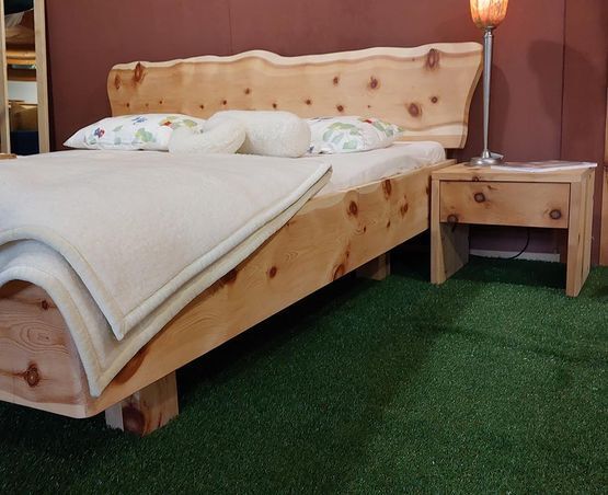 Holzbett mit passendem Nachttisch und Lampe, helle Bettwäsche