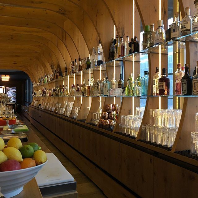 Bar-Interieur mit geschwungener Holzdecke und Regalen voller Spirituosenflaschen