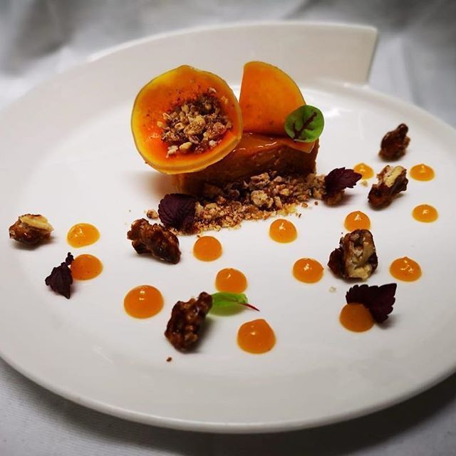 Gourmet-Dessert auf einem weißen Teller: ein karamellfarbenes Quadrat mit Früchten