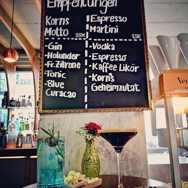 Eine Kreidetafel mit Getränkeempfehlungen. Davor stehen zwei Cocktails.