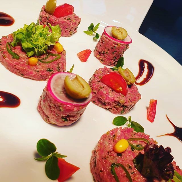 Rindertartar, garniert mit Tomaten, Oliven, Radieschen, Salat und Sauce