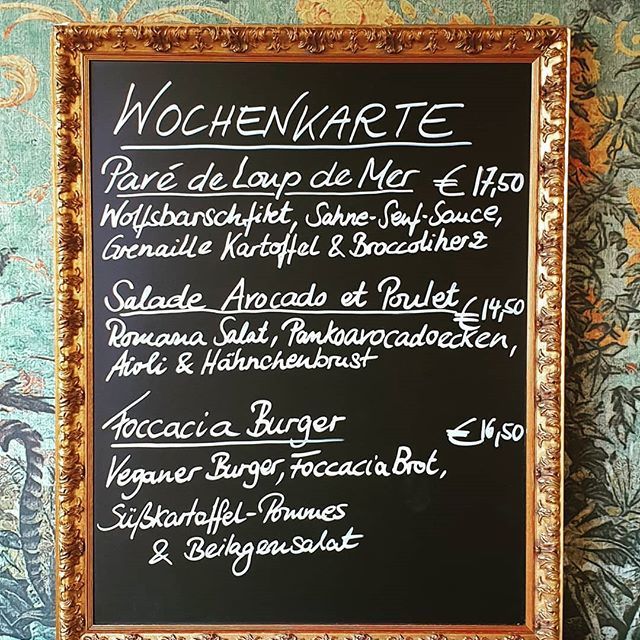 Speisekarte auf der Kreidetafel: Wolfsbarschfilet, Avocado-Hühnersalat, Focaccia-Burger. 
