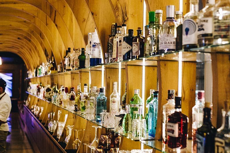 Eine Bar mit Flaschen in Regalen in einer geschwungenen Holzwand