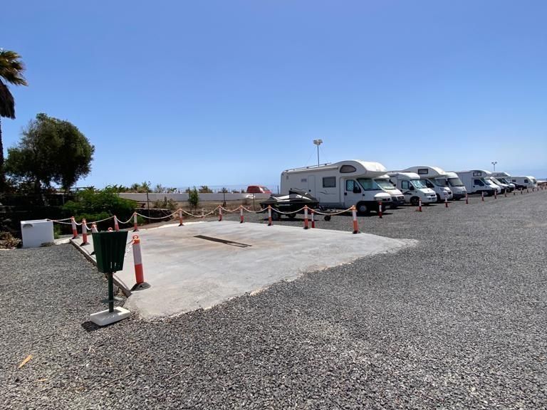 Una fila de vehículos recreativos están estacionados en un lote de grava.