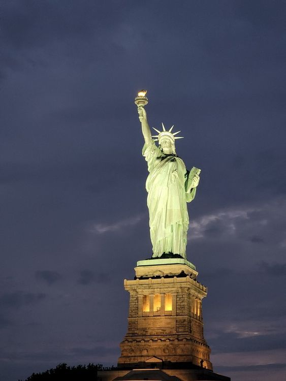 La estatua de la libertad está iluminada por la noche.