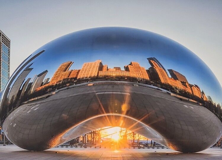 Una gran escultura con el horizonte de la ciudad reflejado en ella.