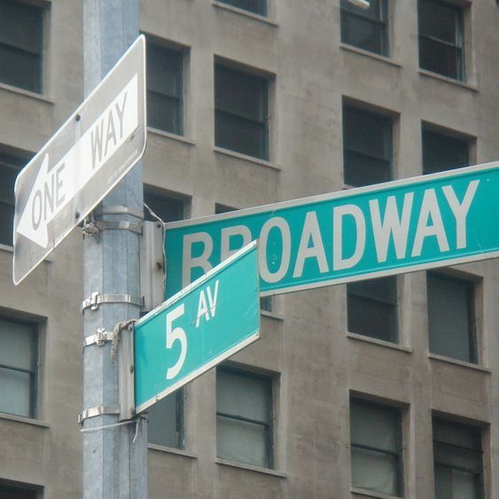 Una señal de un solo sentido y una señal de Broadway en un poste