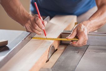 Un hombre está midiendo un trozo de madera con una cinta métrica y un lápiz.