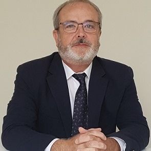 Un hombre con barba y gafas lleva traje y corbata.