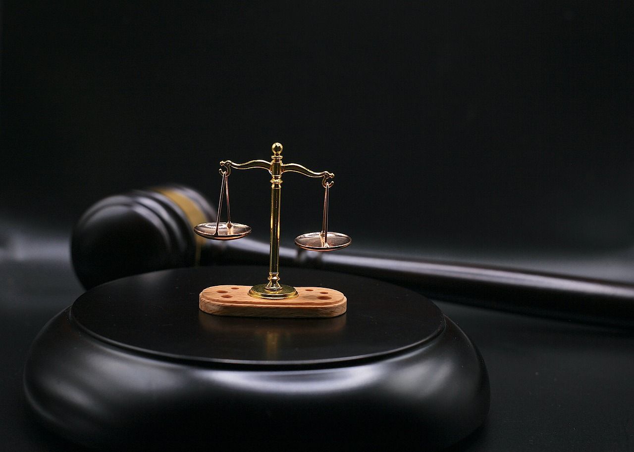 Una balanza de la justicia está colocada sobre un bloque de madera al lado del mazo de un juez.