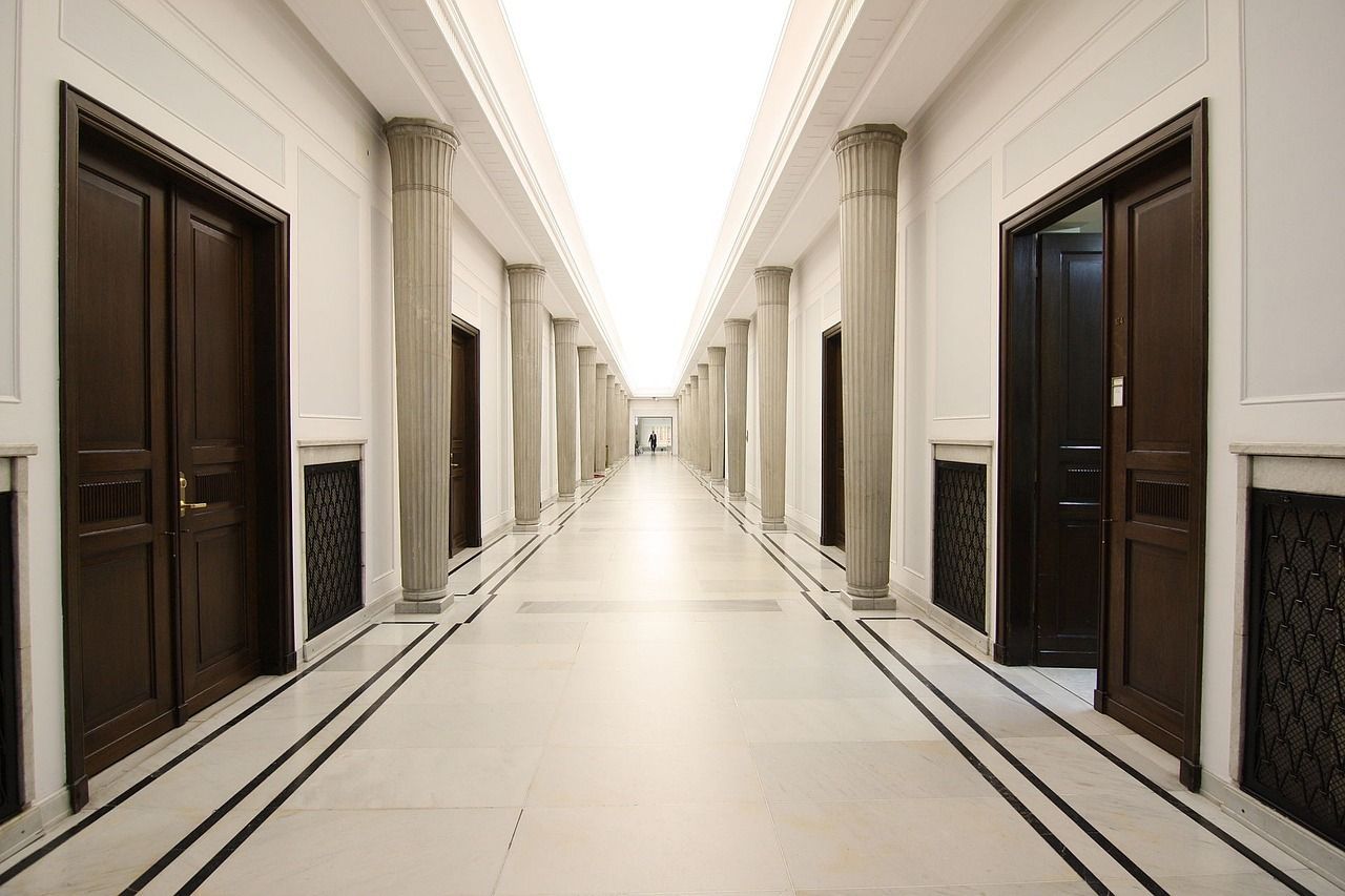 Un largo pasillo con columnas y puertas en un edificio.