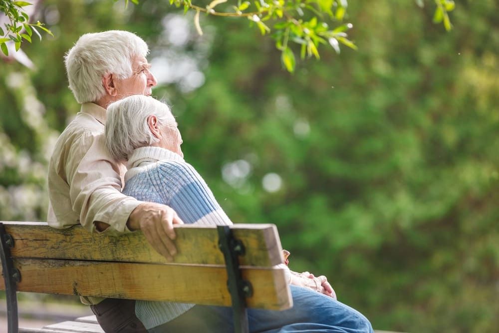 Ein älteres Ehepaar sitzt auf einer Parkbank.